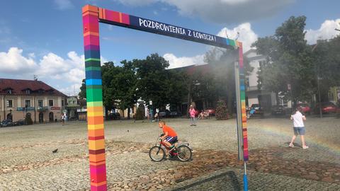 Es ist nicht, wie es scheint. Die bunten Farben auf dem Marktplatz von Łowicz nördöstlich von Łódź verweisen auf traditionelle Volkskunst – nicht auf die LGBT-Flagge. Zu sehen: Ein Spielplatz in Lowicz, Polen. Ein Kind auf einem Fahrrad durchquert das Bild. 