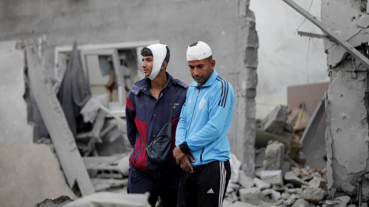 Zwei junge Männer mit verbundenen Kopfverletzungen vor zerstörten Häusern im Gazastreifen. 