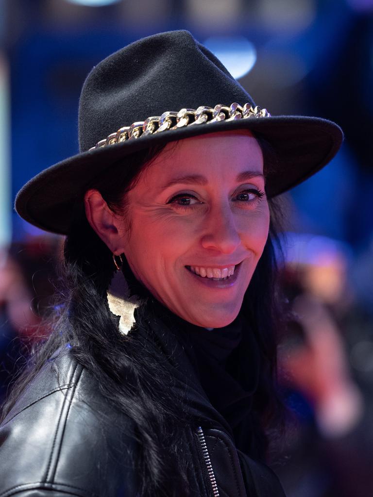 Esther Perbandt trägt einen schwarzen Hut, eine schwarze Lederjacke und schaut lachend in die Kamera.