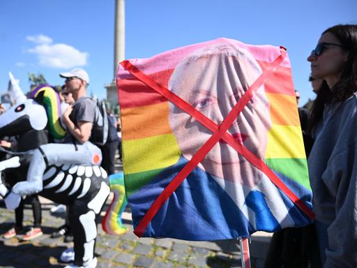 Demonstrantin hält durchgestrichenes Bild mit geschminkten ungarischen Premierministers Viktor Orban auf einer Regenbogenfahne (12.4.2025)