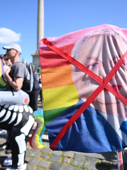 Demonstrantin hält durchgestrichenes Bild mit geschminkten ungarischen Premierministers Viktor Orban auf einer Regenbogenfahne (12.4.2025)