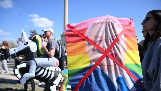 Demonstrantin hält durchgestrichenes Bild mit geschminkten ungarischen Premierministers Viktor Orban auf einer Regenbogenfahne (12.4.2025)
