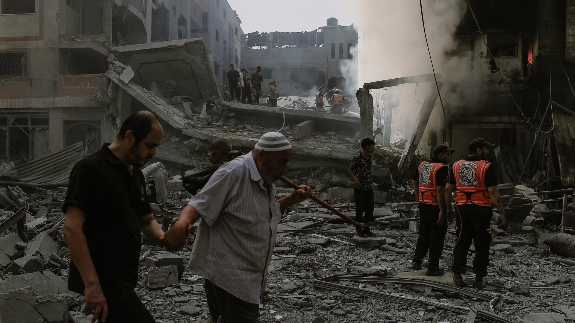 Ein alter Mann geht auf einen jungen Mann gestützt durch die Ruine eines Hauses nach einem Bombenangriff im Gazastreifen.