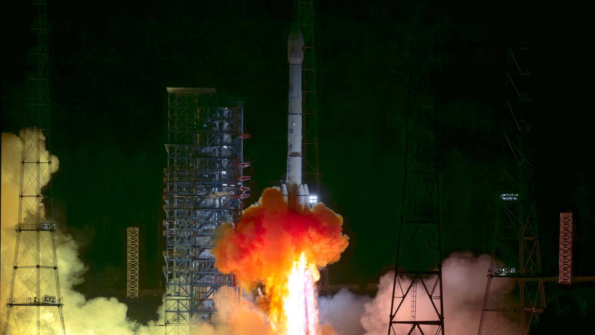 Die Sonde Tianwen-2 auf ihrer Trägerrakete, die beim Start Feuer ausstößt Die Sonde Tianwen-2 auf ihrer Trägerrakete, die beim Start Feuer ausstößt