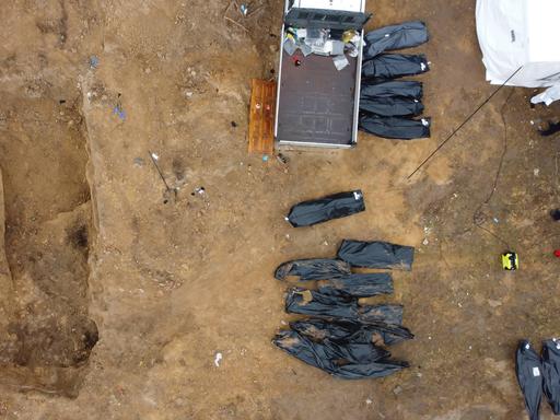 Schwarze Leichensäcke liegen neben einem Transporter im ukrainischen Ort Butscha, wo Leichen aus einem Massengrab geborgen wurden.