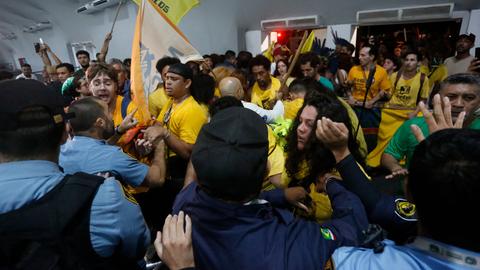 Sicherheitskräfte halten Protestierende zurück. 