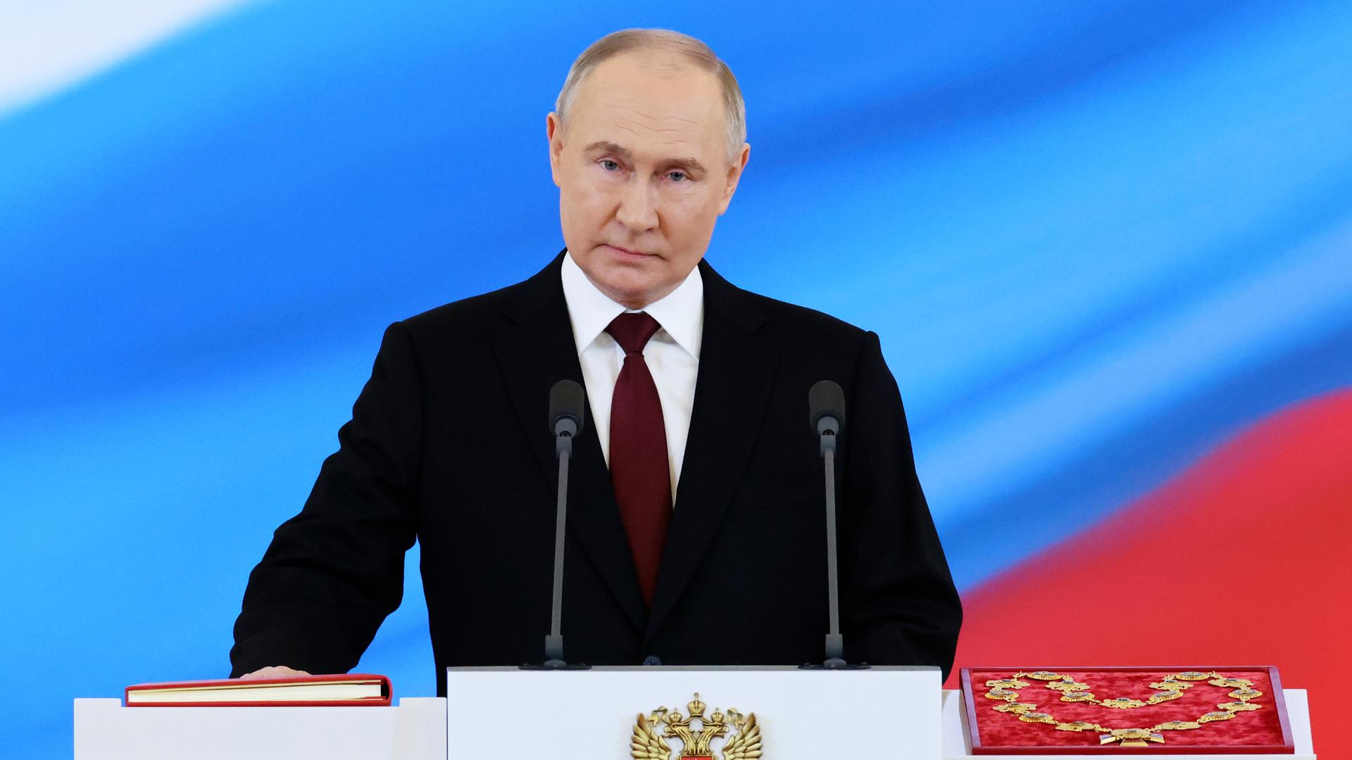 Putin steht an einem Pult und hält bei der Vereidigung die rechte Hand auf die Verfassung.