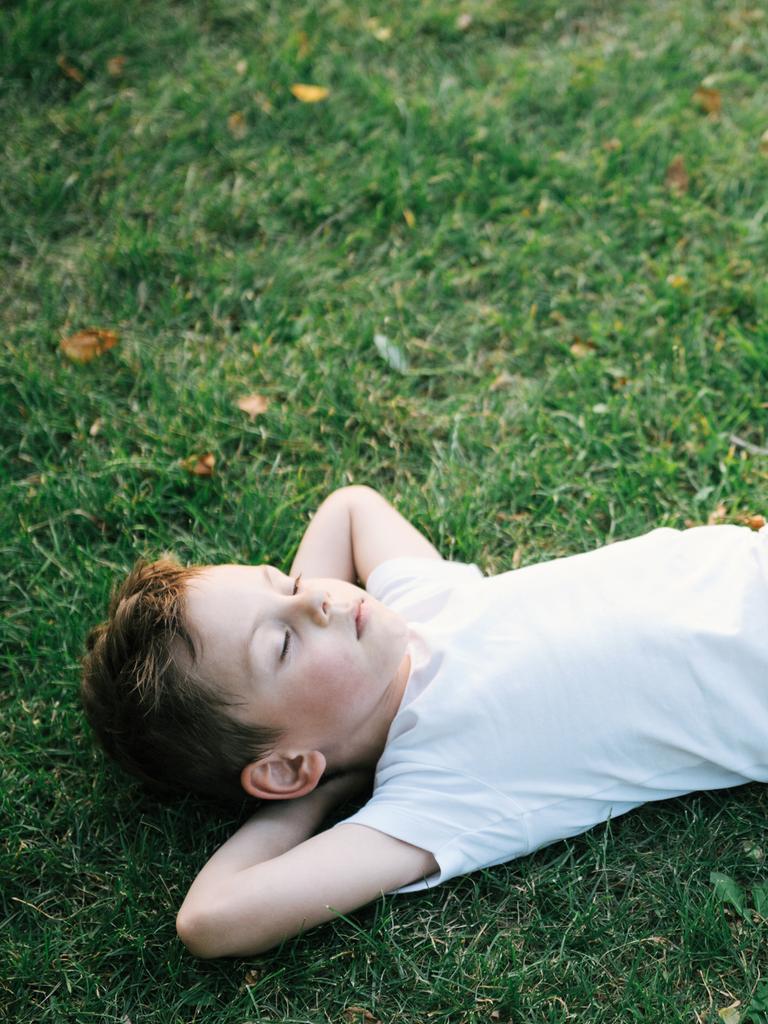Ein Junge liegt mit verschränkten Armen faul auf einer Wiese.