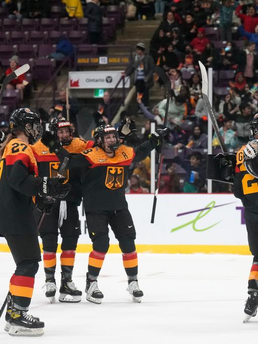 Mehrere Eishockey-Spielerinnen mit deutschem Trikot jubeln nach einem Tor.