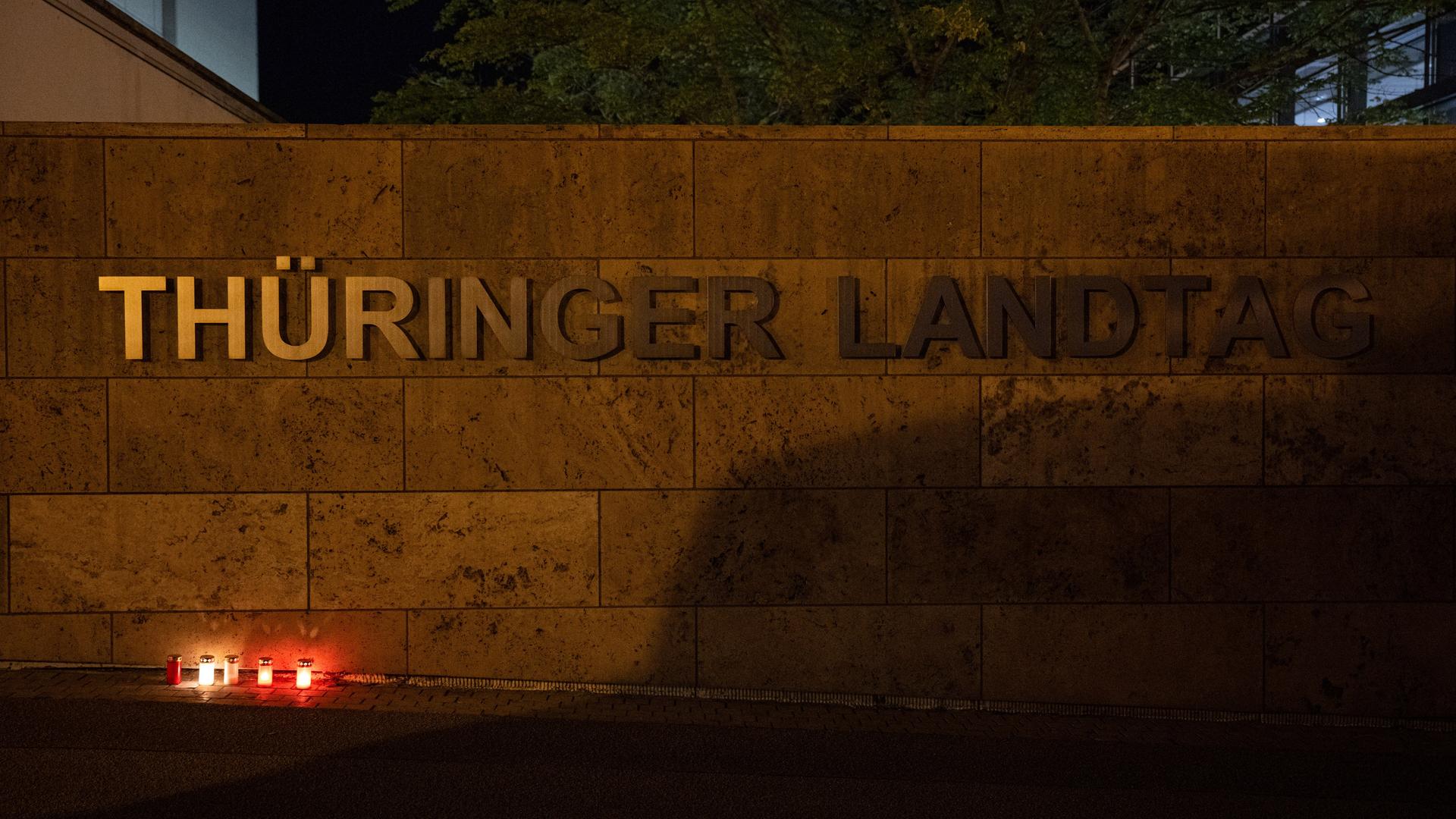 Grablichter stehen am späten Abend vor dem Schriftzug am Thüringer Landtag.