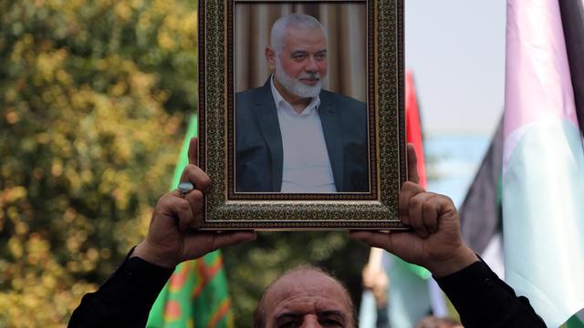 Ein Mann hält ein Bild in den Händen. Auf dem Foto ist der Anführer der Hamas abgebildet: Ismail Hanija.