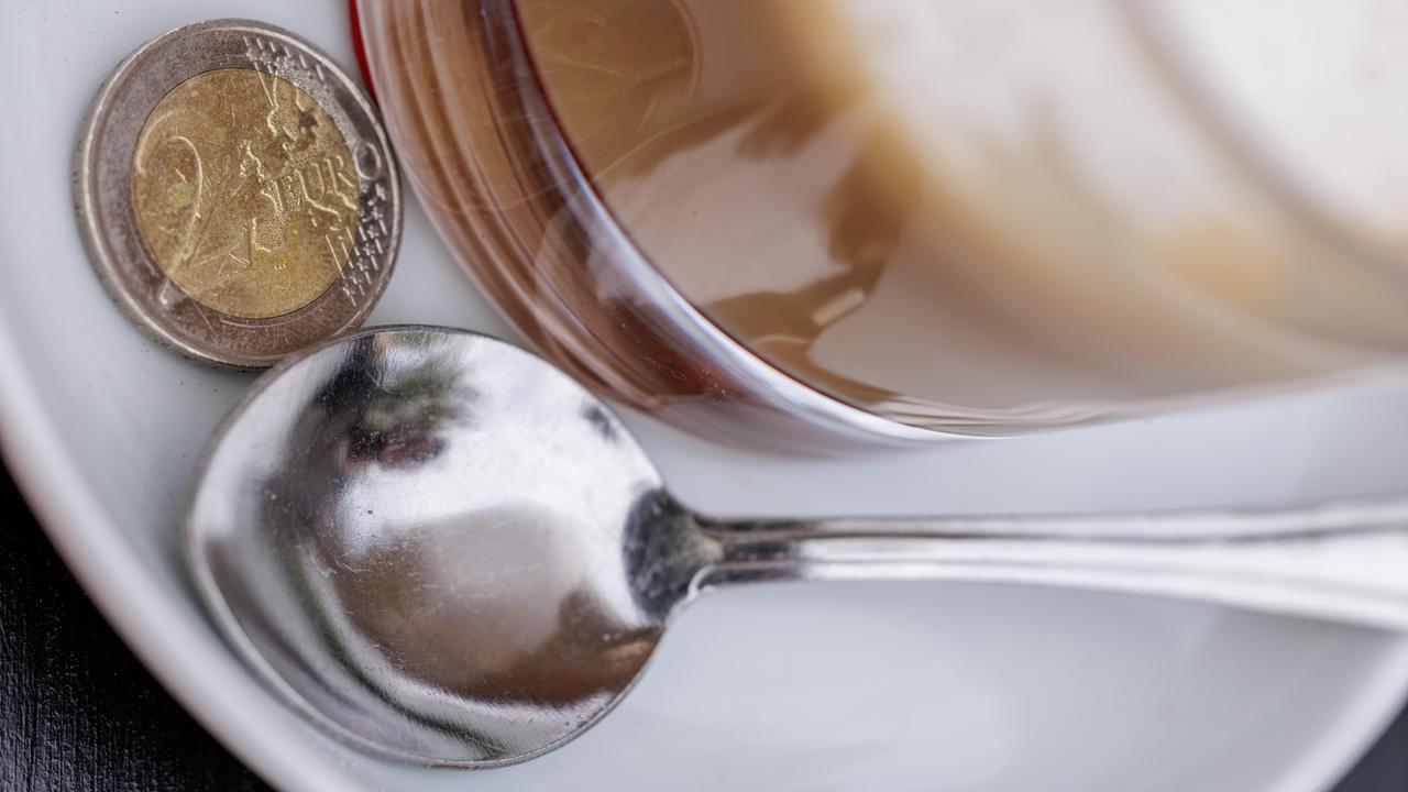 Ein Zwei Euro Stück liegt auf der Untertasse eines Kaffees.