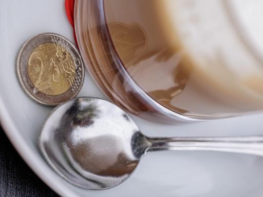Ein Zwei Euro Stück liegt auf der Untertasse eines Kaffees. Ein Zwei Euro Stück liegt auf der Untertasse eines Kaffees.