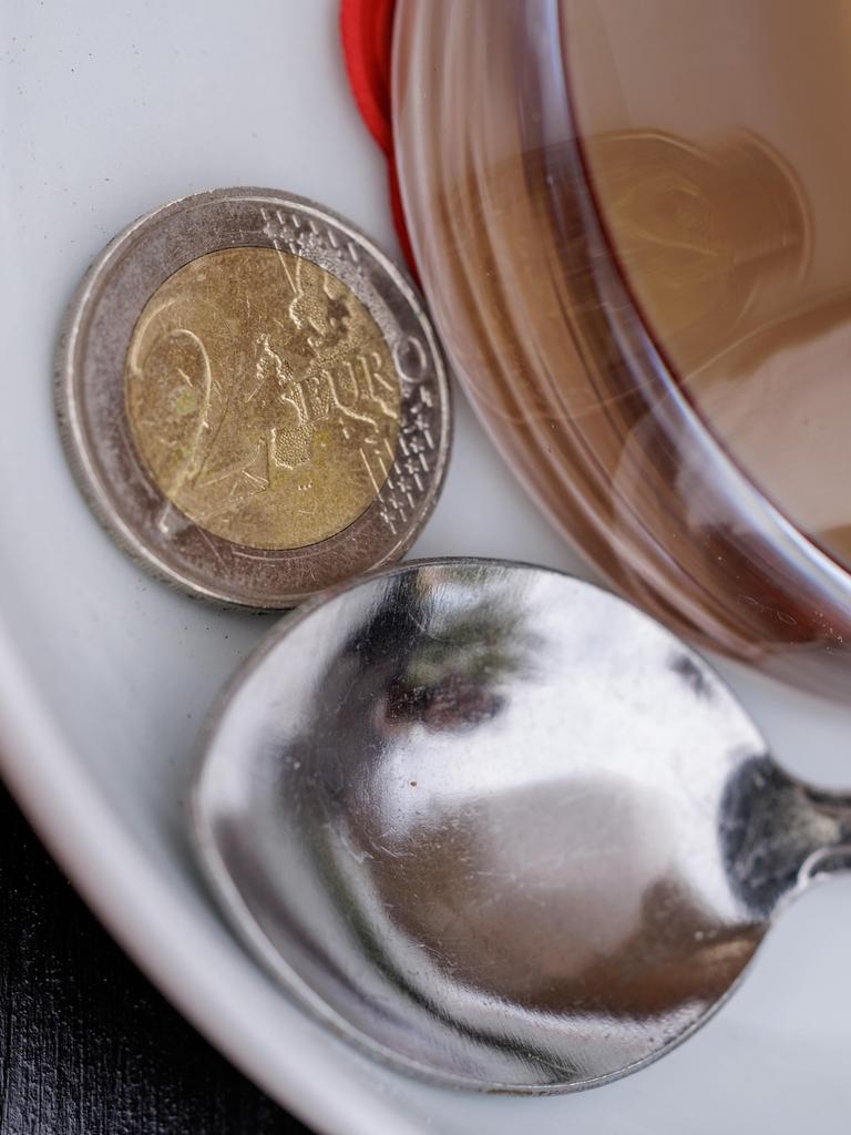 Ein Zwei Euro Stück liegt auf der Untertasse eines Kaffees. Ein Zwei Euro Stück liegt auf der Untertasse eines Kaffees.
