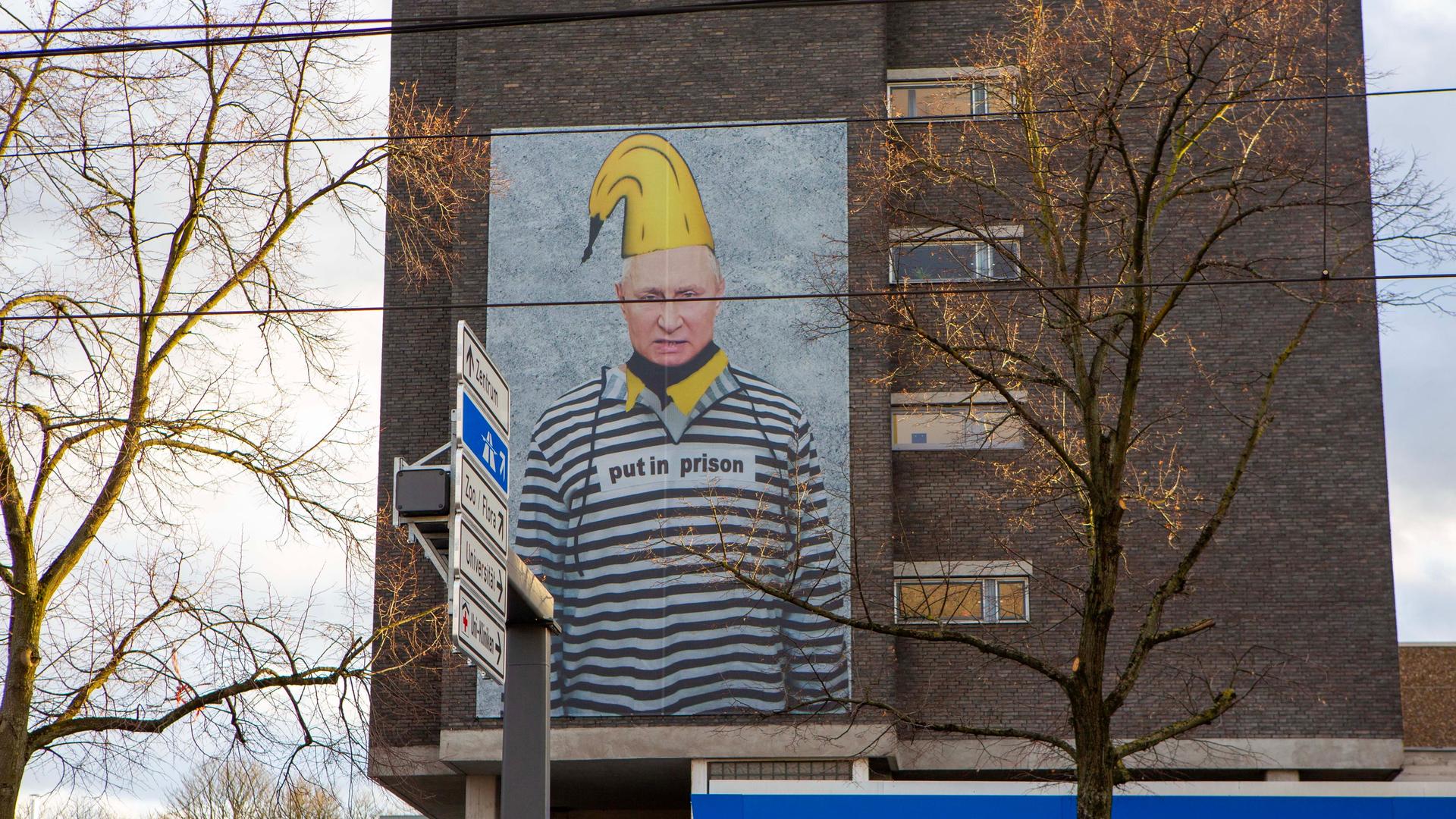 Das Bildnis des russischen Präsidenten Wladimir Putin in Häftlingskleidung ist in Übergröße auf einer Hauswand in Köln zu sehen. Der Internationale Strafgerichtshof (ICC) hat vor einem Jahr einen Haftbefehl gegen Wladimir Putin erlassen wegen der Deportation ukrainischer Kinder.