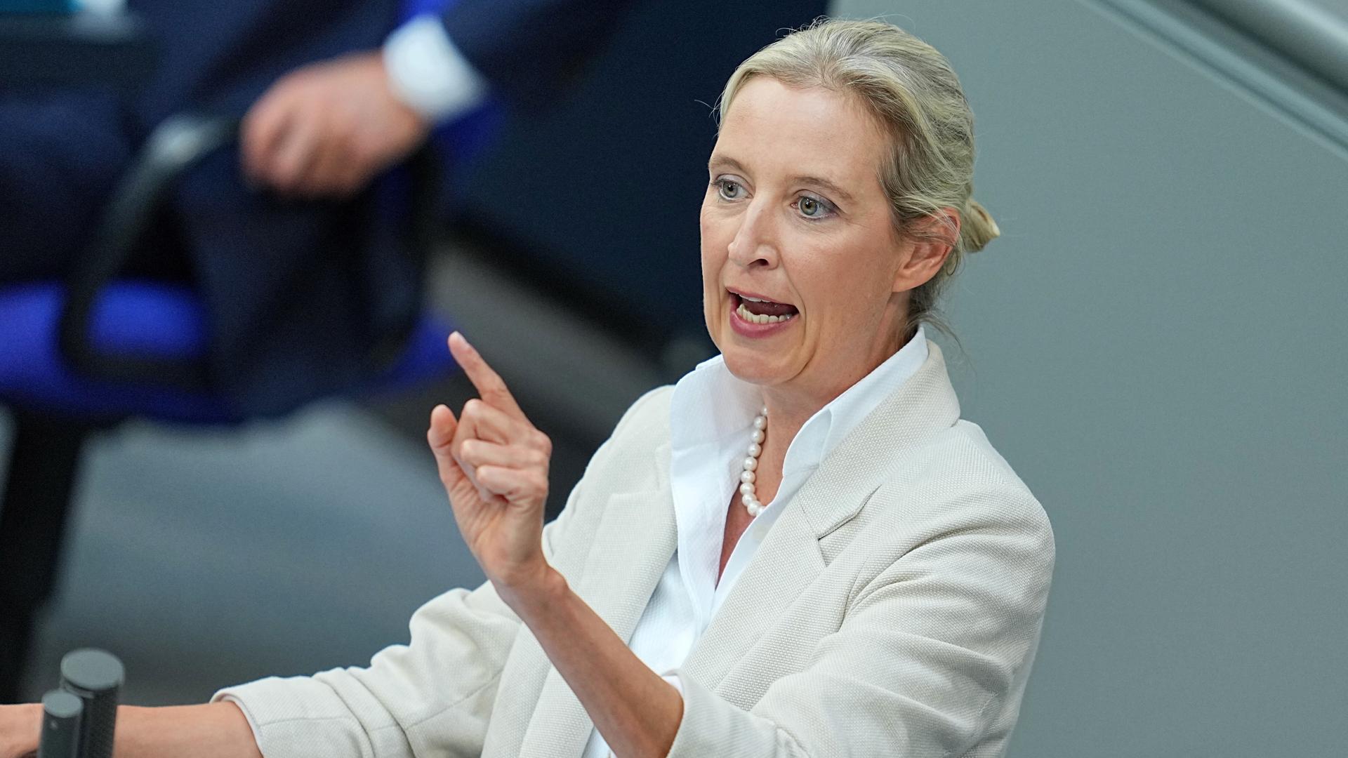 Weidel im weißen Kostüm spricht am Rednerpult und deutet mit dem Zeigefinger der rechten Hand nach vorne. Weidel im weißen Kostüm spricht am Rednerpult und deutet mit dem Zeigefinger der rechten Hand nach vorne.