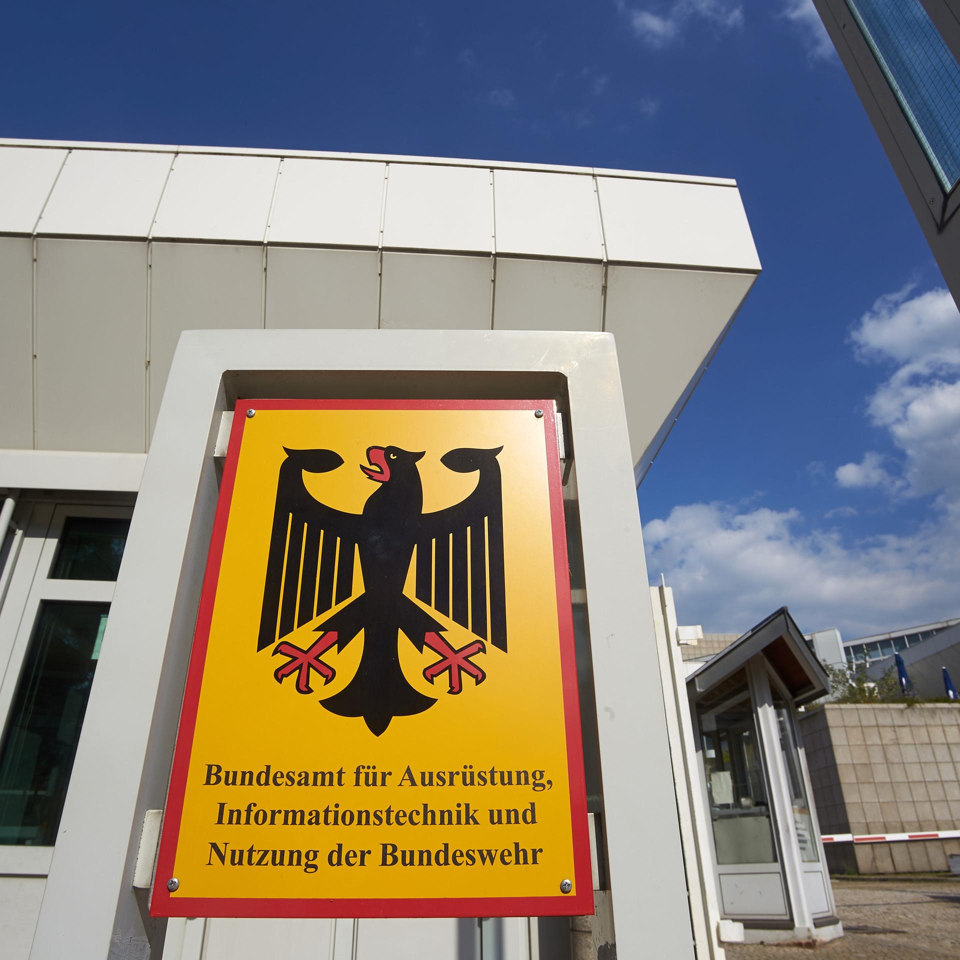 Die Außenfassade eines Gebäudes des Bundesamts für Ausrüstung, Informationstechnik und Nutzung der Bundeswehr, im Vordergrund befindet sich ein Schild mit dem Namen der Behörde.