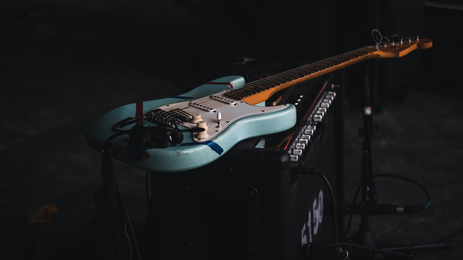 Eine blau-weiße E-Gitarre liegt auf einem Verstärker.