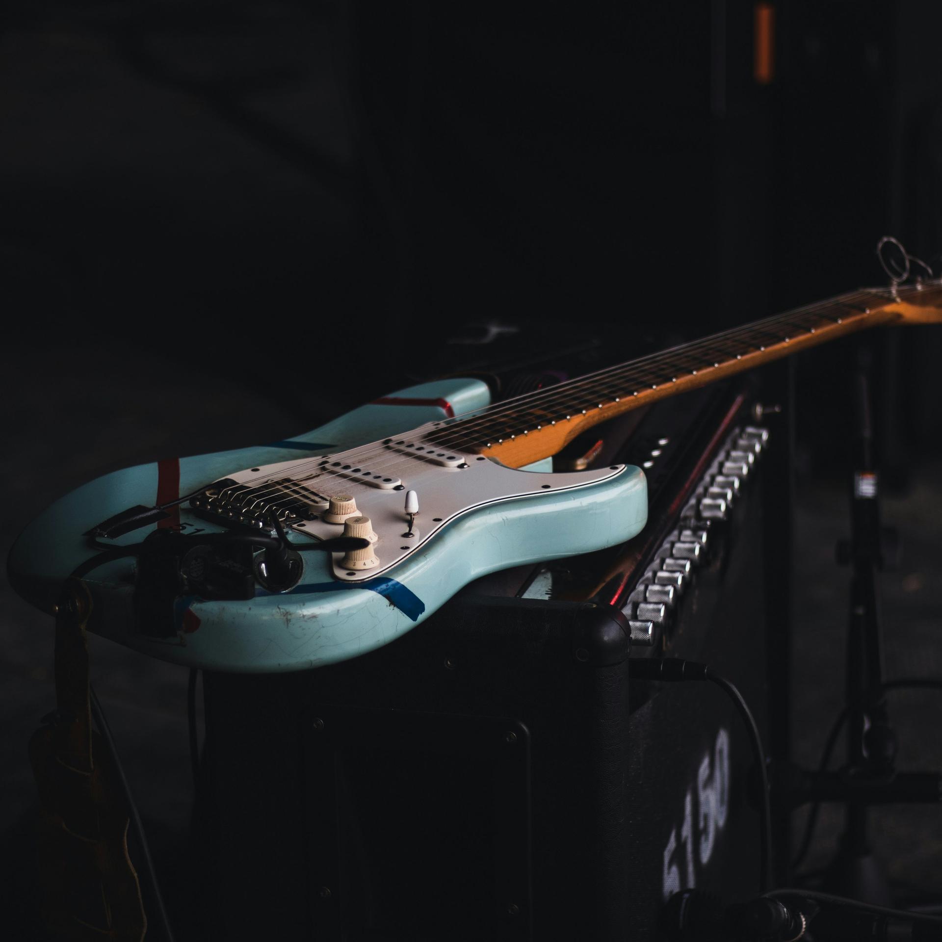 Eine blau-weiße E-Gitarre liegt auf einem Verstärker.