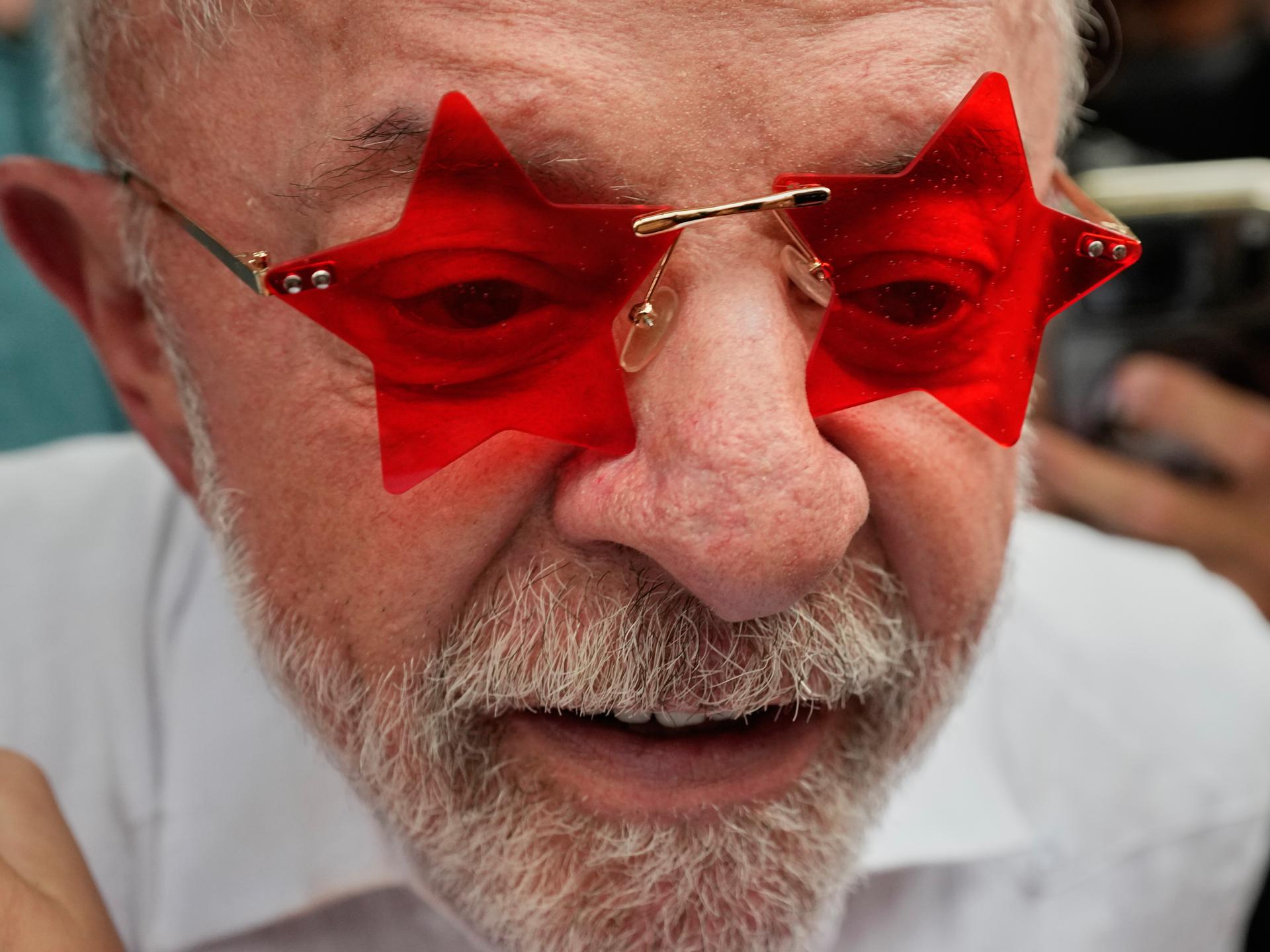 Ein Mann in weißem Hemd trägt eine Sonnenbrille, bei der die Gläser die Form eines Sterns haben. Die Gläser sind rot. Es ist der brasilianische Präsident Luiz Inácio Lula da Silva.
