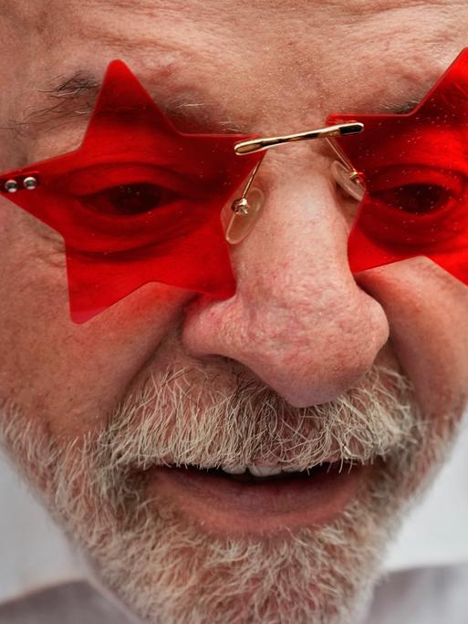 Ein Mann in weißem Hemd trägt eine Sonnenbrille, bei der die Gläser die Form eines Sterns haben. Die Gläser sind rot. Es ist der brasilianische Präsident Luiz Inácio Lula da Silva.