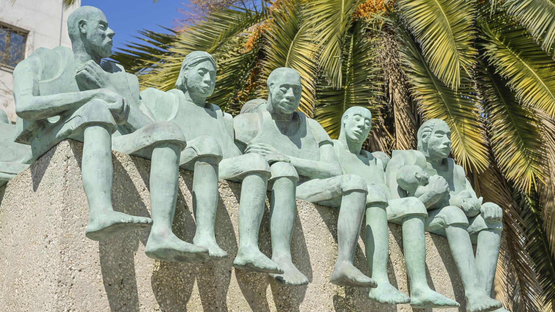 Fünf große grüne Figuren, die nebeneinander sitzen, zeigt diese Ansicht eines Denkmals in Madrid