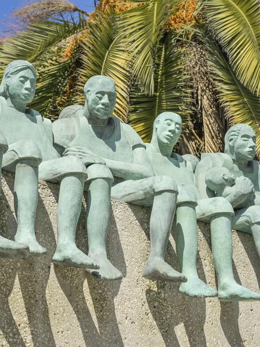 Fünf große grüne Figuren, die nebeneinander sitzen, zeigt diese Ansicht eines Denkmals in Madrid Fünf große grüne Figuren, die nebeneinander sitzen, zeigt diese Ansicht eines Denkmals in Madrid