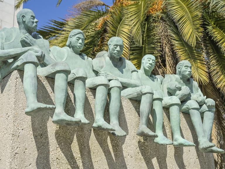 Fünf große grüne Figuren, die nebeneinander sitzen, zeigt diese Ansicht eines Denkmals in Madrid Fünf große grüne Figuren, die nebeneinander sitzen, zeigt diese Ansicht eines Denkmals in Madrid