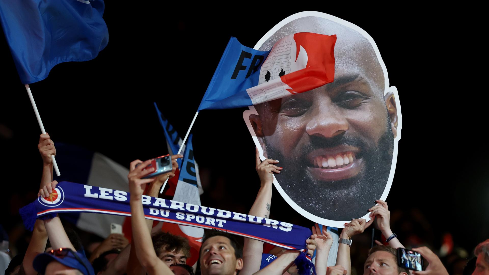 Französischen Zuschauer halten ein Plakat mit dem Konterfei von Judoka Teddy Riner aus Frankreich hoch.