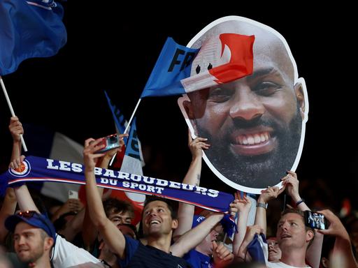 Französischen Zuschauer halten ein Plakat mit dem Konterfei von Judoka Teddy Riner aus Frankreich hoch.