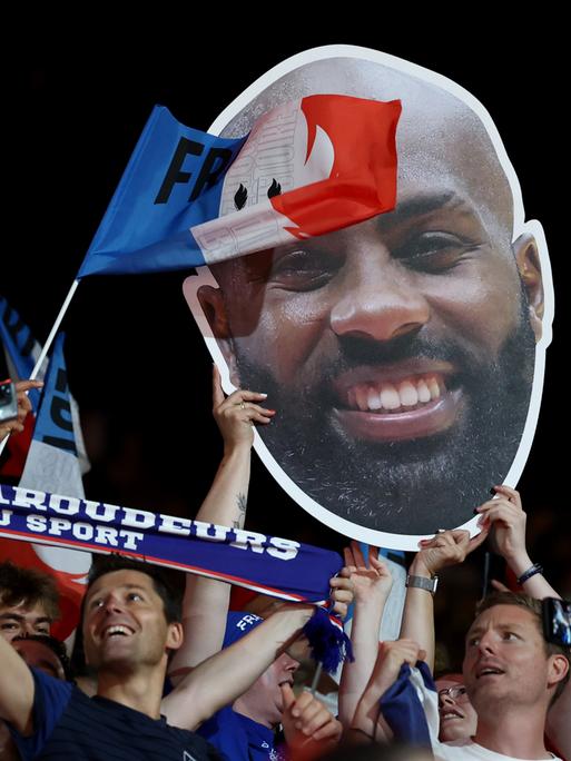 Französischen Zuschauer halten ein Plakat mit dem Konterfei von Judoka Teddy Riner aus Frankreich hoch.