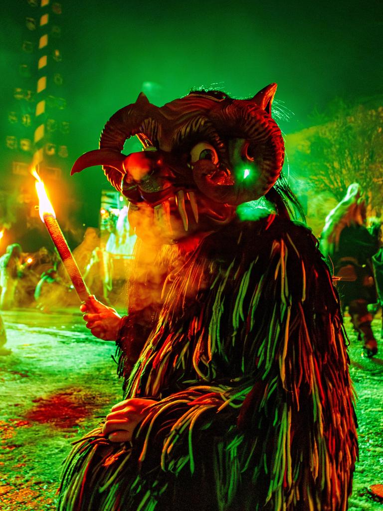 Kostümierte Person mit Maske und Fackel beim Kirchseeoner Perchten in Oberbayern Kostümierte Person mit Maske und Fackel beim Kirchseeoner Perchten in Oberbayern