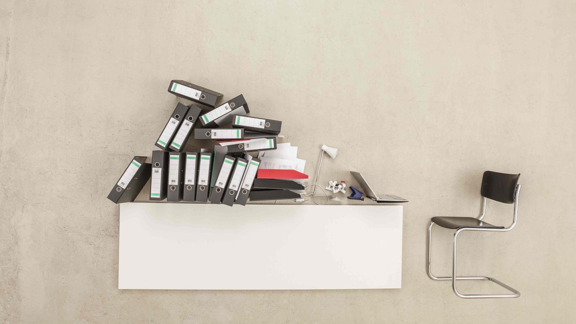 Auf einem Schreibtisch stapeln sich Aktenordner