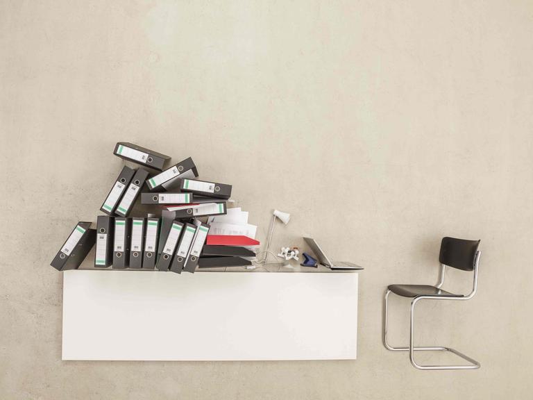 Auf einem Schreibtisch stapeln sich Aktenordner