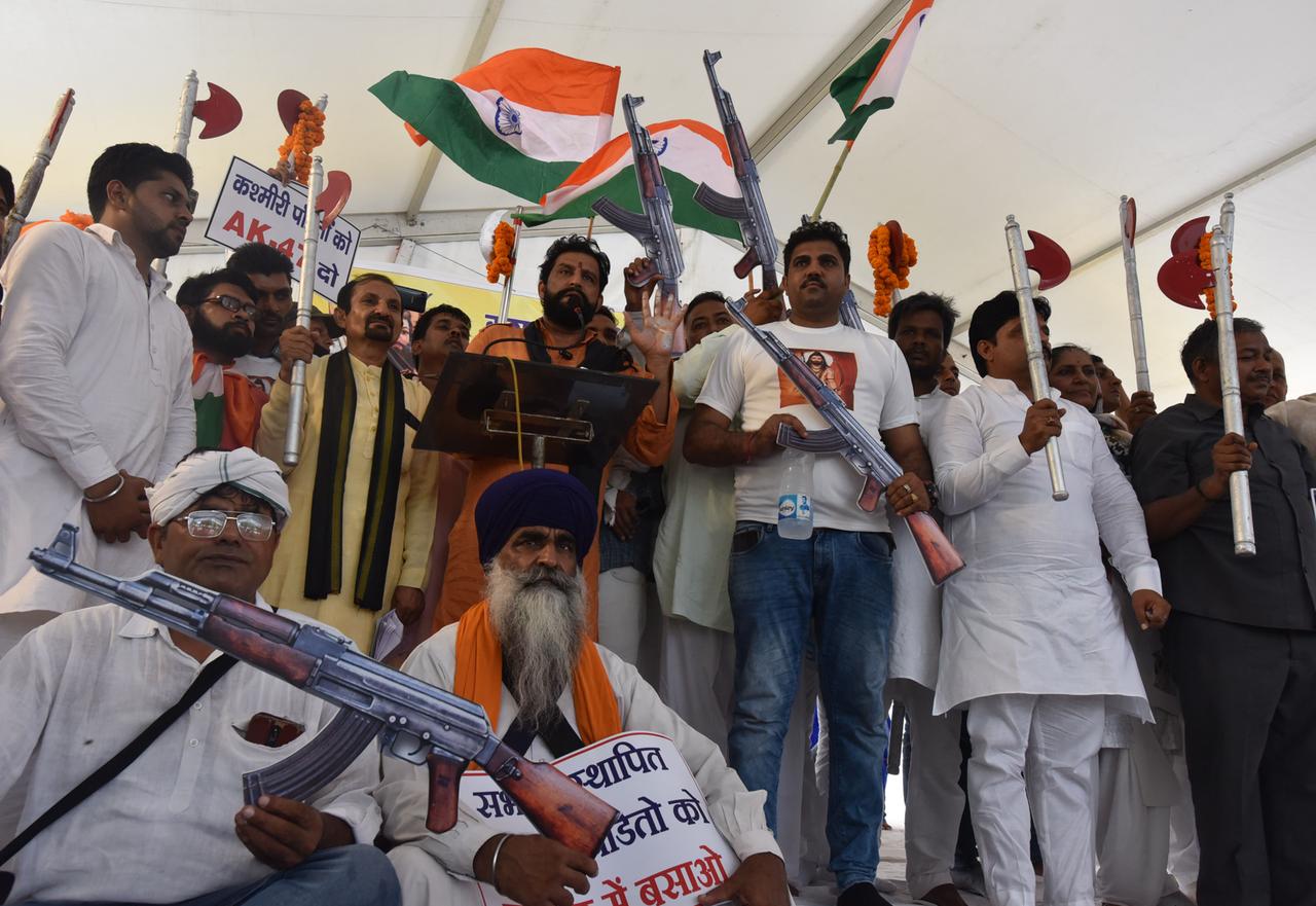 Zahlreiche Männer protestieren unter der Führung von Naveen Jaihind gegen die brutalen Morde an Kaschmir-Hindus, Pandits, Soldaten, Angestellten und den Exodus von Hindus aus dem Kaschmir-Tal. Dabei recken sie Maschinengewehre vom Typ Ak-47 in die Luft und schwenken die indische Flagge.