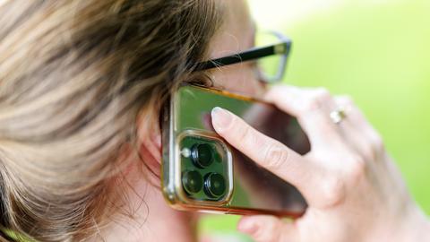 Eine junge Frau steht in einem Garten und telefoniert mit ihrem Smartphone. Eine junge Frau steht in einem Garten und telefoniert mit ihrem Smartphone.