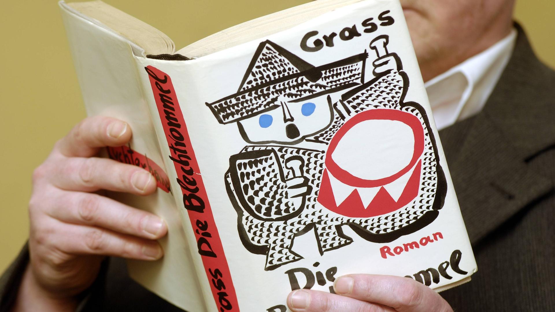 Ein Mann liest das Buch "Die Blechtrommel" und hält es aufgeklappt vor sich. Ein Mann liest das Buch "Die Blechtrommel" und hält es aufgeklappt vor sich.