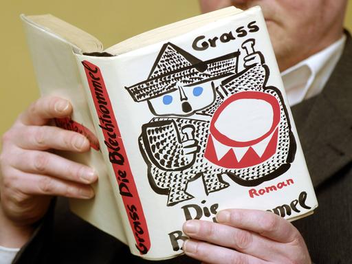 Ein Mann liest das Buch "Die Blechtrommel" und hält es aufgeklappt vor sich.