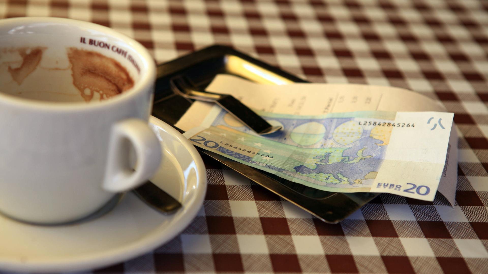 Leere Kaffeetasse mit Rechnung und Geldschein auf dem Tisch