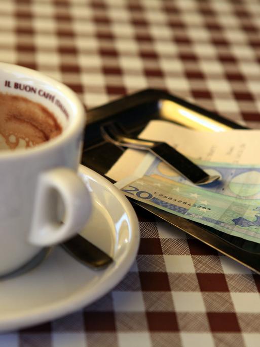 Leere Kaffeetasse mit Rechnung und Geldschein auf dem Tisch