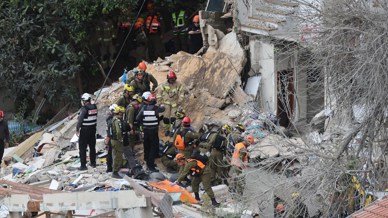 Rettungskräfte stehen auf den Trümmern eines Hauses.