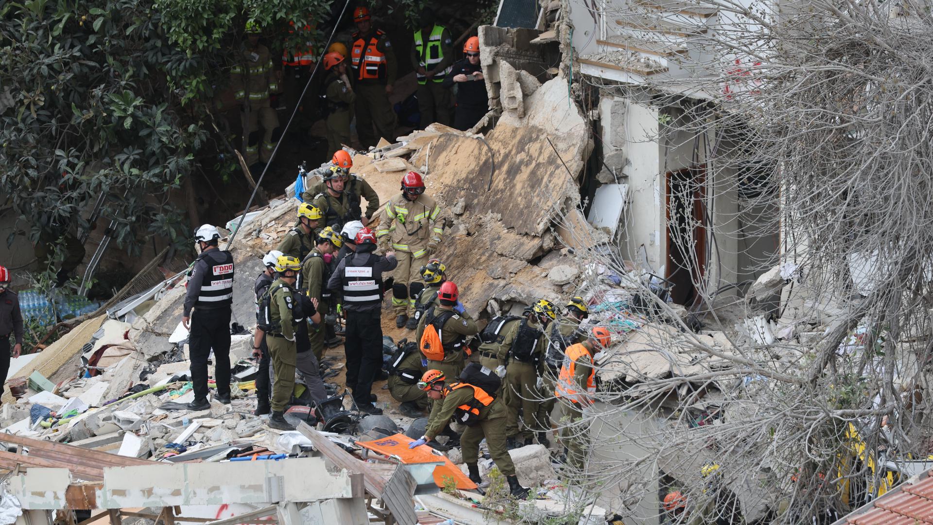 Rettungskräfte stehen auf den Trümmern eines Hauses.