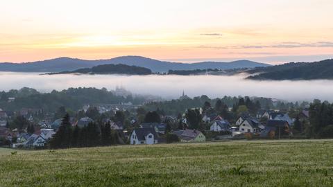 Ortsansicht mit Kirche St. Mariä Himmelfahrt im Morgennebel noch vor Sonnenaufgang, Schirgiswalde, Oberlausitzer Bergland, Sachsen.