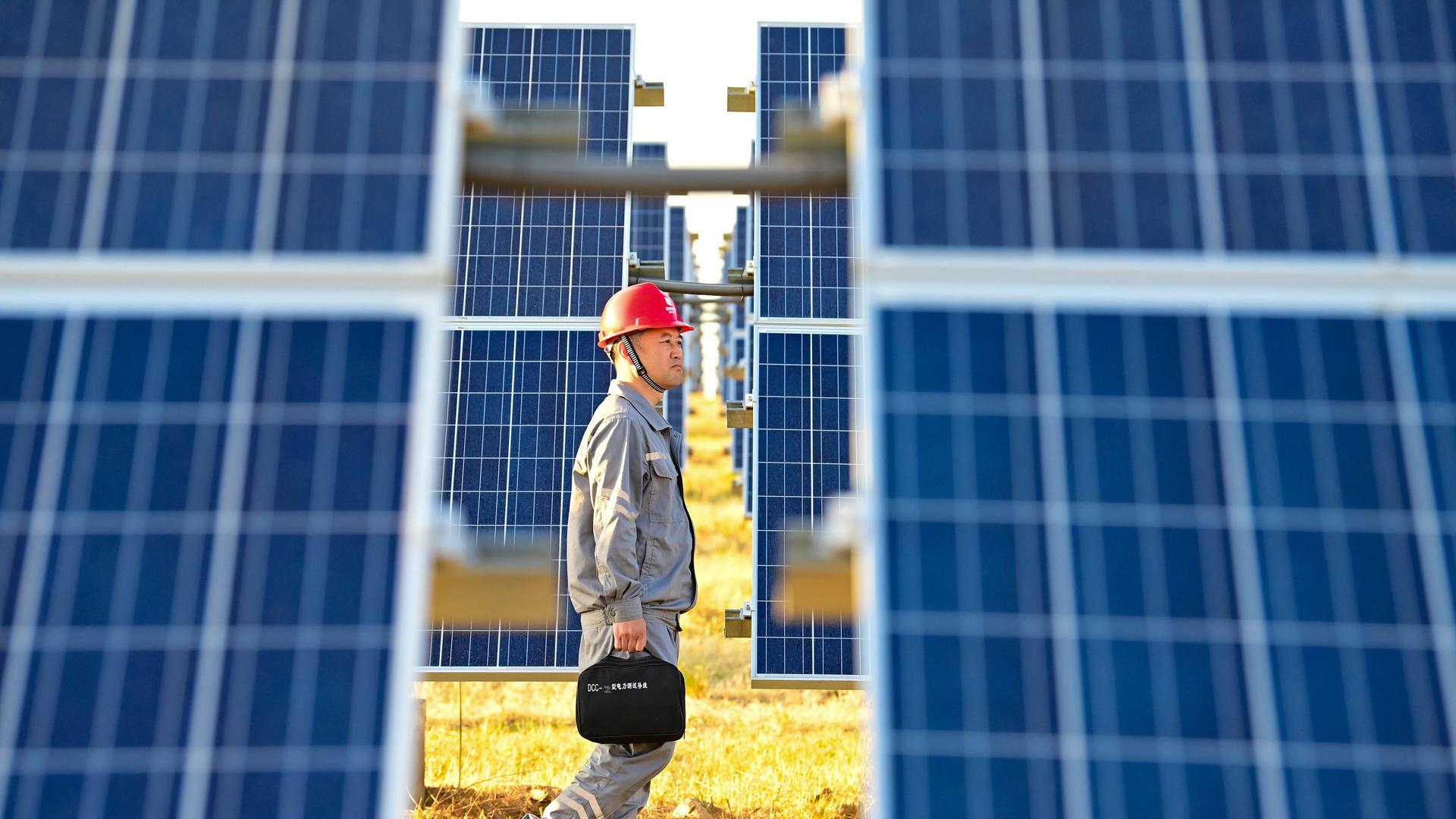 In Ulanhot, in China, läuft ein Arbeiter zwischen Solar-Panels hindurch.