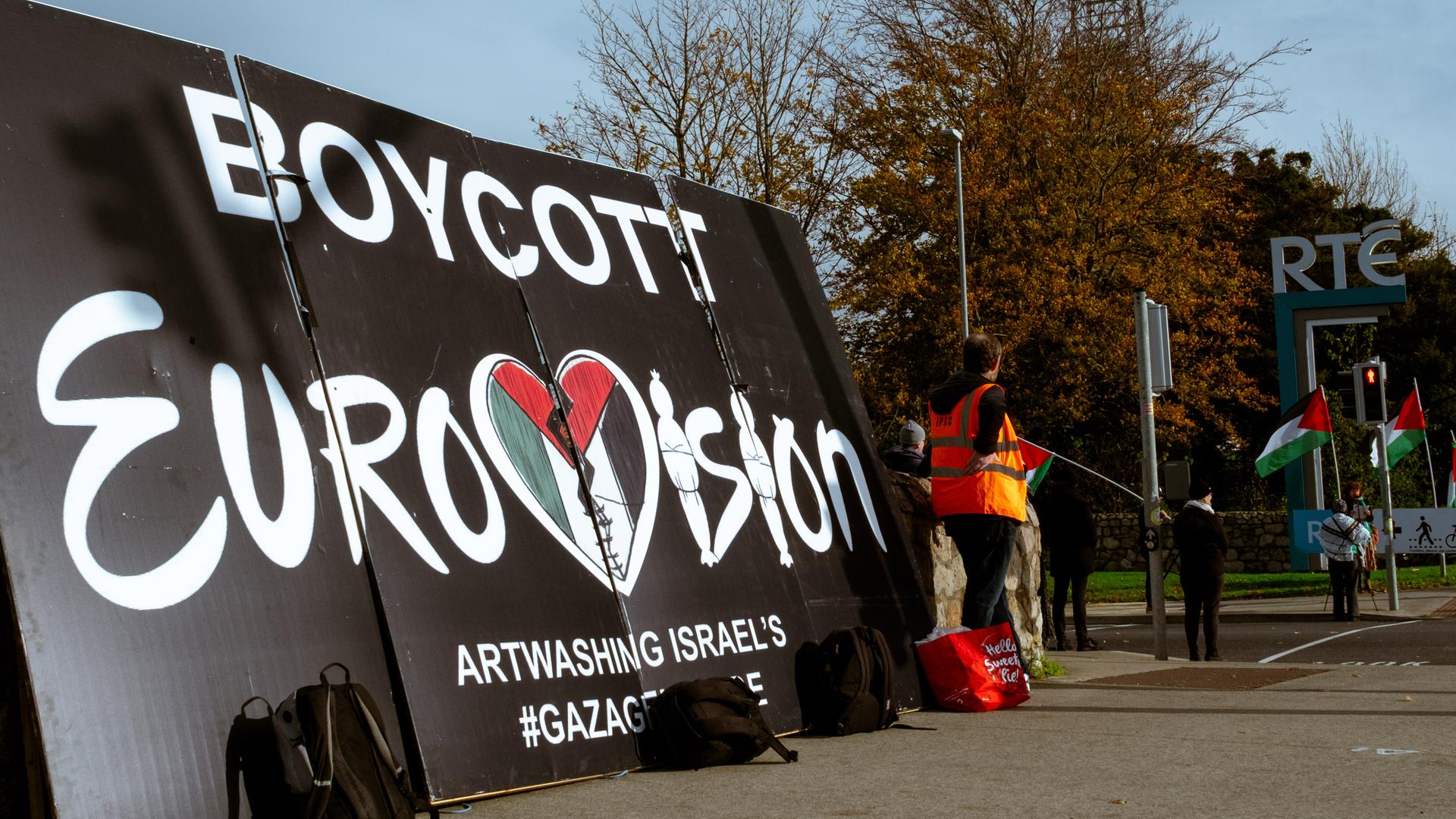 Auf einem Plakatt steht: "Boykott Eurovision". Daneben stehen einige Demonstranten.