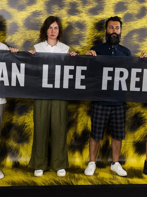 Alec Barth, Lea Luttenberger, Produzent Sina Ataeian Dena und Dorna Dibaj (v.l.n.r.) tragen einen Banner mit der Aufschrift „Woman Life Freedom“ während eines Fototermins für den Film "(Critical Zone"“ des iranischen Filmregisseurs Ali Ahmadzadeh. 