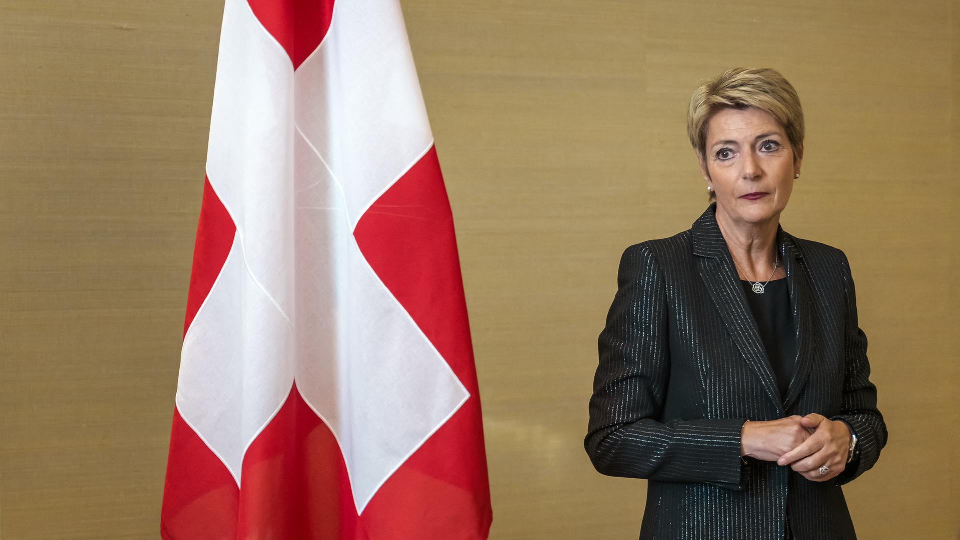 Die Schweizer Bundespräsidentin Karin Keller-Sutter schaut nachdenklich. Neben ihr ist eine Flagge der Schweiz zu sehen.