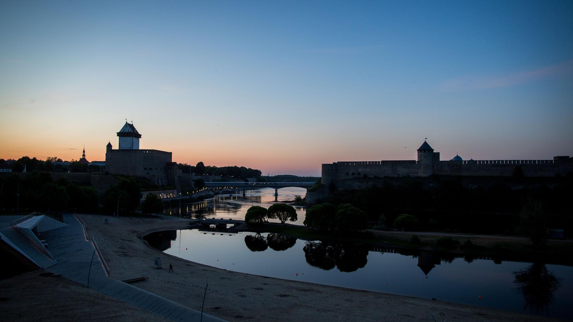 Die Sonne geht in der estnischen Stadt Narva und der russischen Burg Iwangorod auf der gegenüberliegenden Seite unter. Die Sonne geht in der estnischen Stadt Narva und der russischen Burg Iwangorod auf der gegenüberliegenden Seite unter.