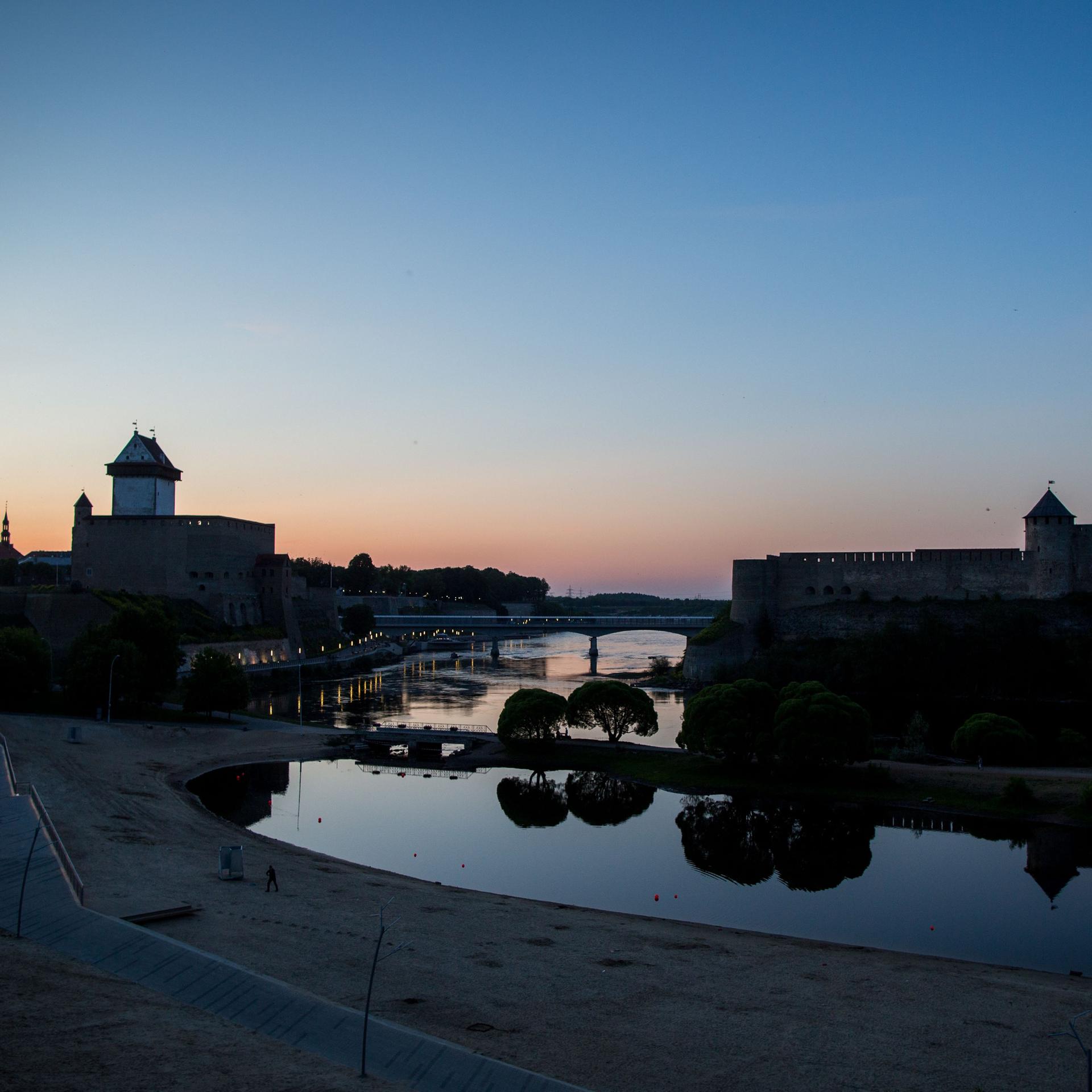 Die Sonne geht in der estnischen Stadt Narva und der russischen Burg Iwangorod auf der gegenüberliegenden Seite unter. 