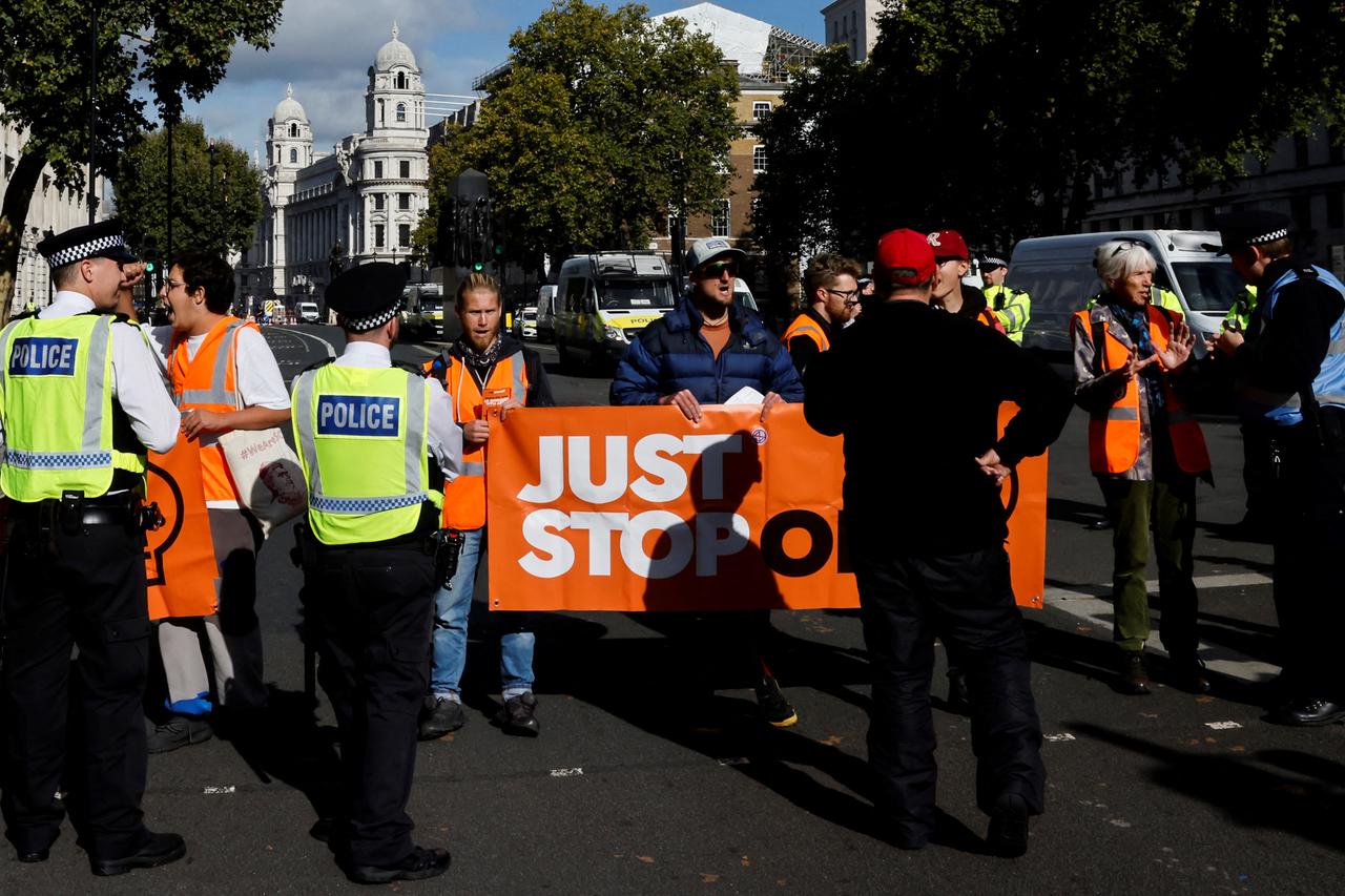 Mitglieder der Organisation "Just Stop Oil" protestieren vor dem Sitz des britischen Premierministers in der Downing Street in London. Sie halten ein Banner mit dem Namen ihrer NGO, davor stehen Polizisten.